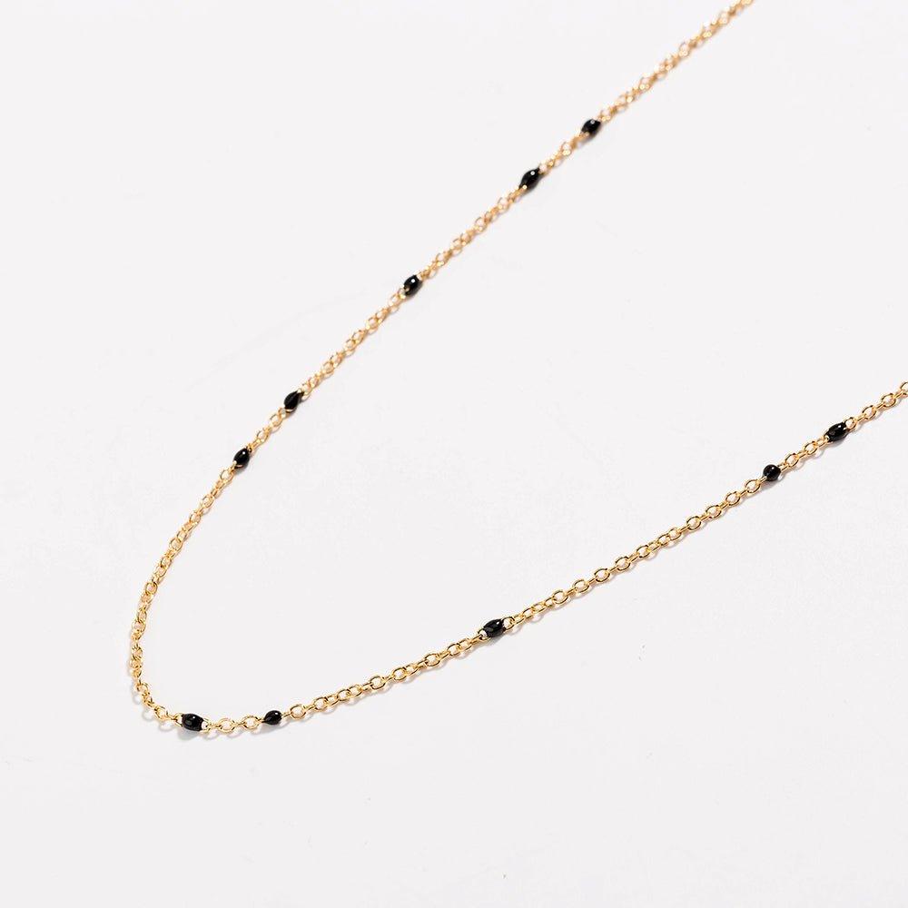 Gold link necklace detail with black bead stations and chain curve