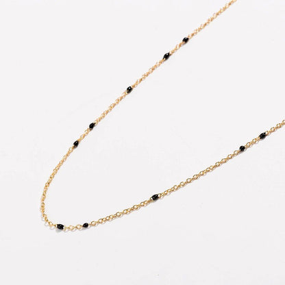 Gold link necklace detail with black bead stations and chain curve