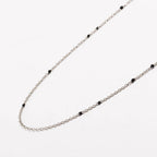 Gold-tone beaded link necklace with small black onyx-style beads, U-shape.