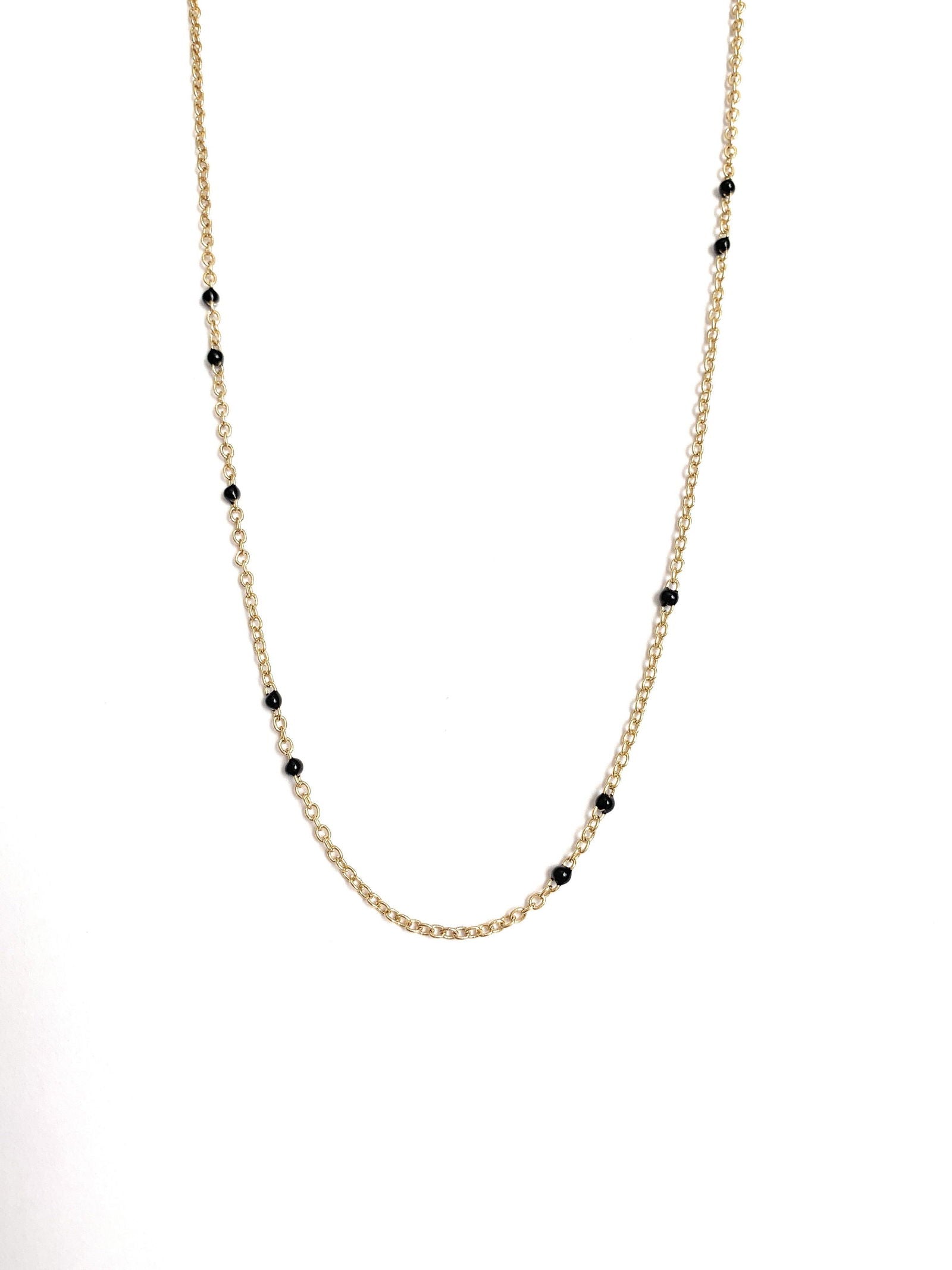 Gold-tone beaded link necklace with black onyx-style beads, partial close-up.