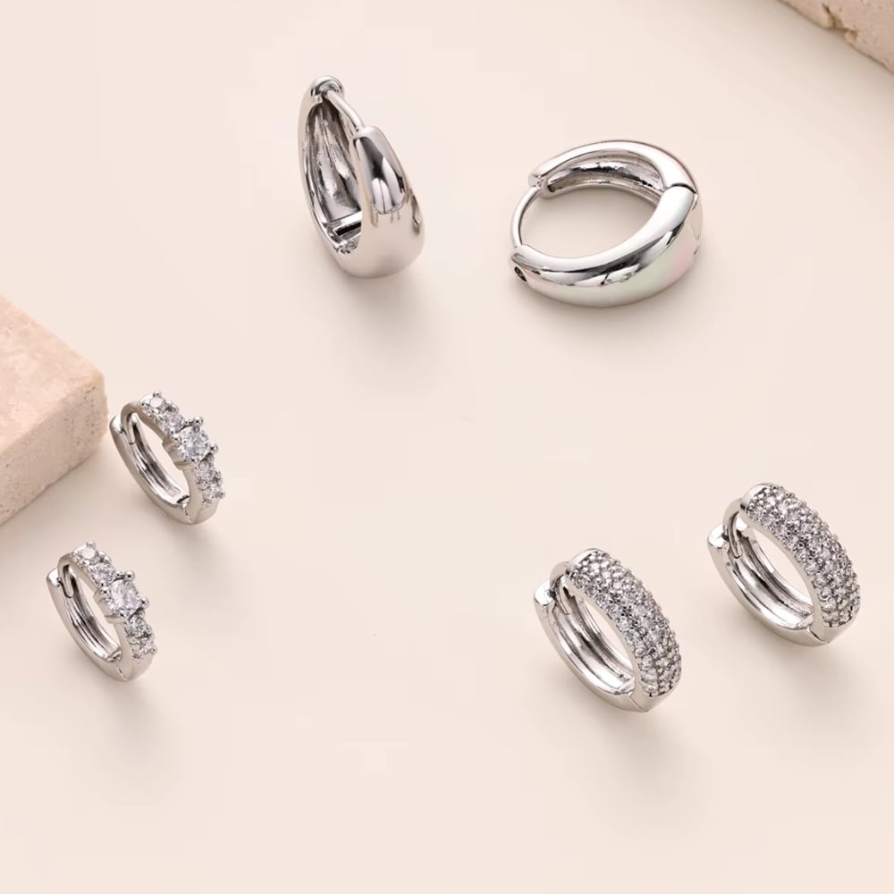 Silver huggie hoop earrings with sparkling stones, shown in a set of pairs