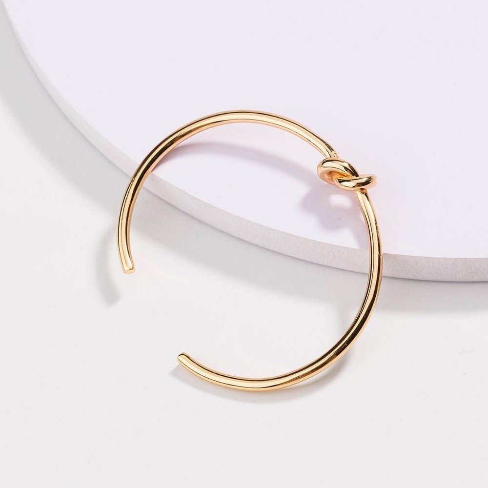 Gold love-knot bracelet with a twisted knot clasp and smooth round bangle