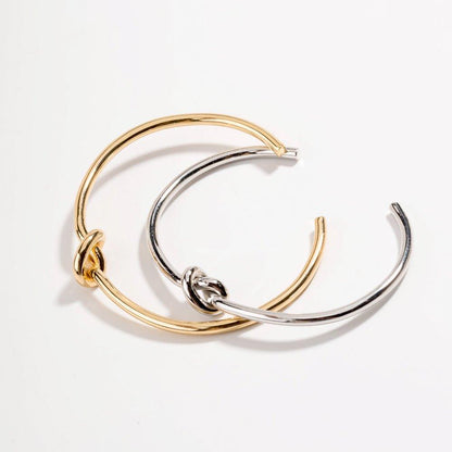 Layered gold and silver love-knot bracelets with twisted knot clasp detail