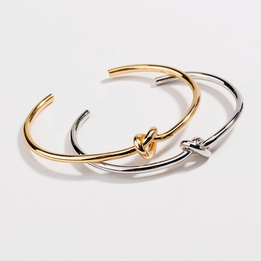 Overlapping gold and silver love-knot bangles with twisted knot clasps