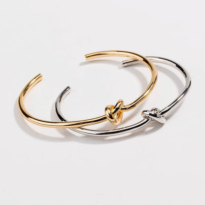 Overlapping gold and silver love-knot bangles with twisted knot clasps