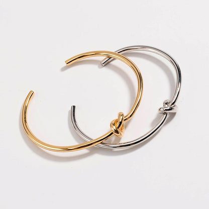 Set of two bangles: gold and silver love-knot bracelets with twisted clasp