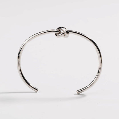 Silver love-knot bracelet with twisted knot clasp on a slim round bangle