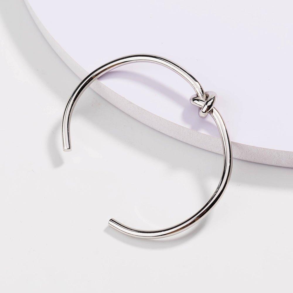 Silver love-knot bracelet with twisted knot closure on a slim round band