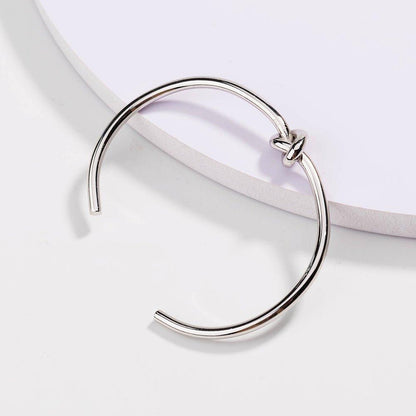 Silver love-knot bracelet with twisted knot closure on a slim round band