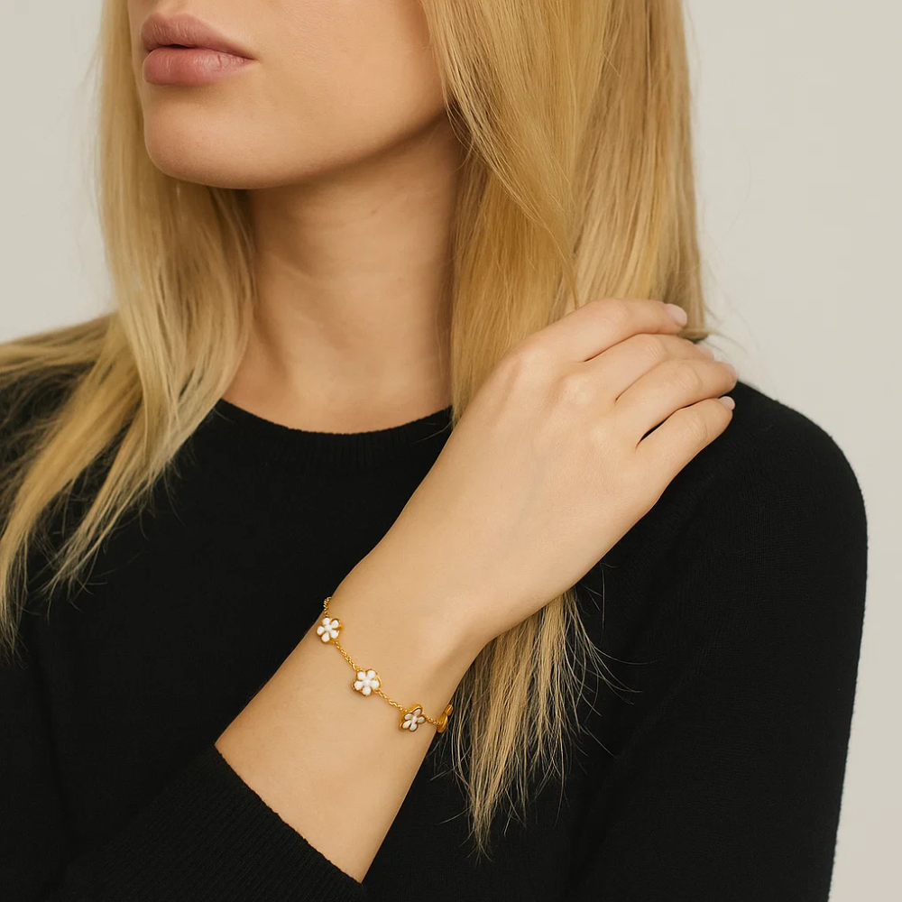 Gold-tone clover charm bracelet worn on wrist, close-up view