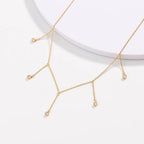 Gold drop necklace with five clear cubic zirconia dangle stones, angled view