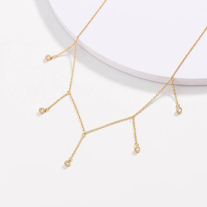 Gold drop necklace with five clear cubic zirconia dangle stones, angled view