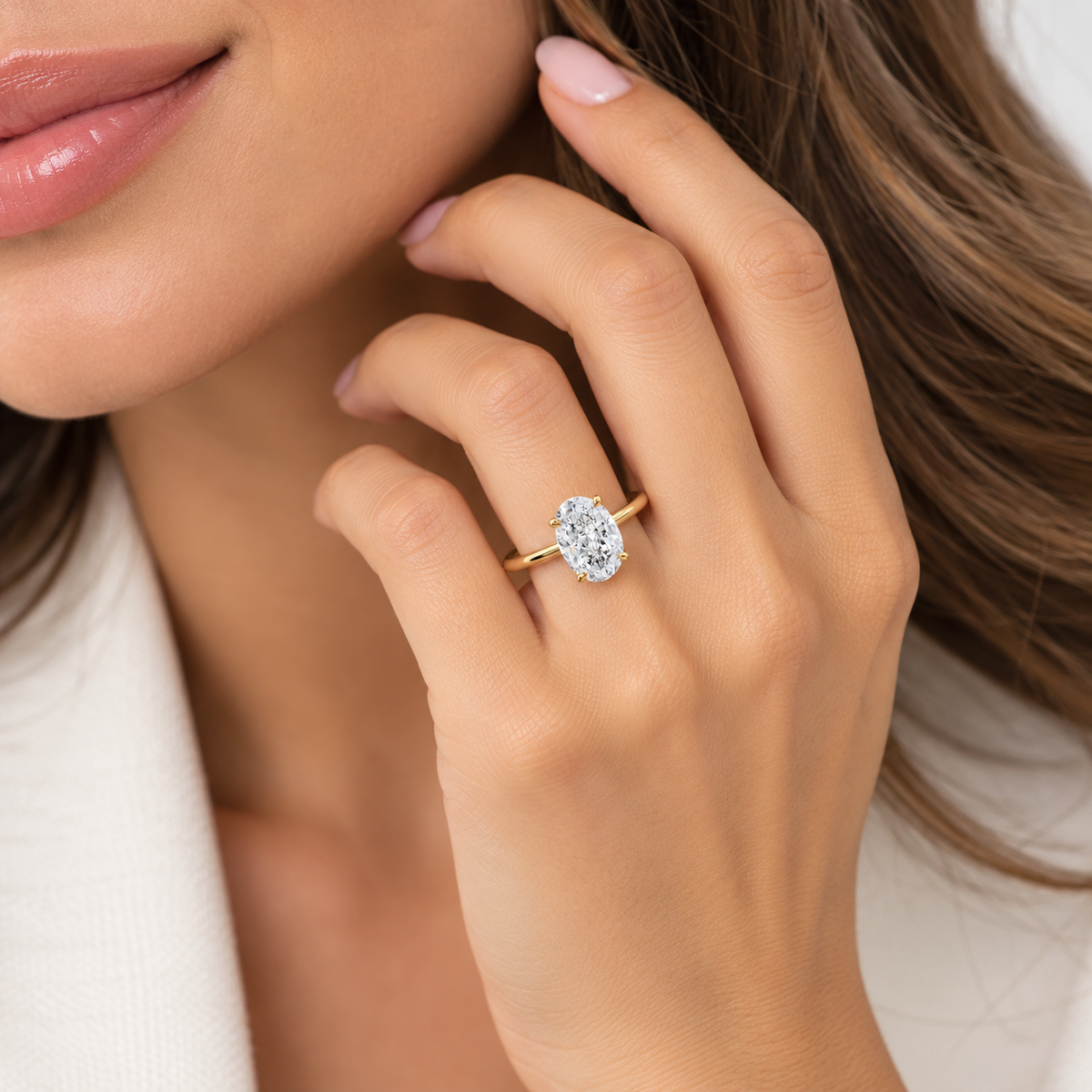 Gold-tone oval solitaire ring on finger, prong-set center stone with halo