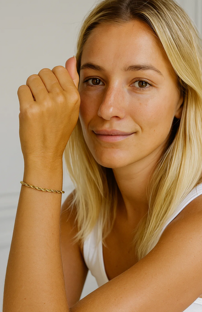 Gold rope bracelet on raised wrist of blonde model