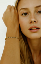 Gold rope bracelet on wrist with close face view