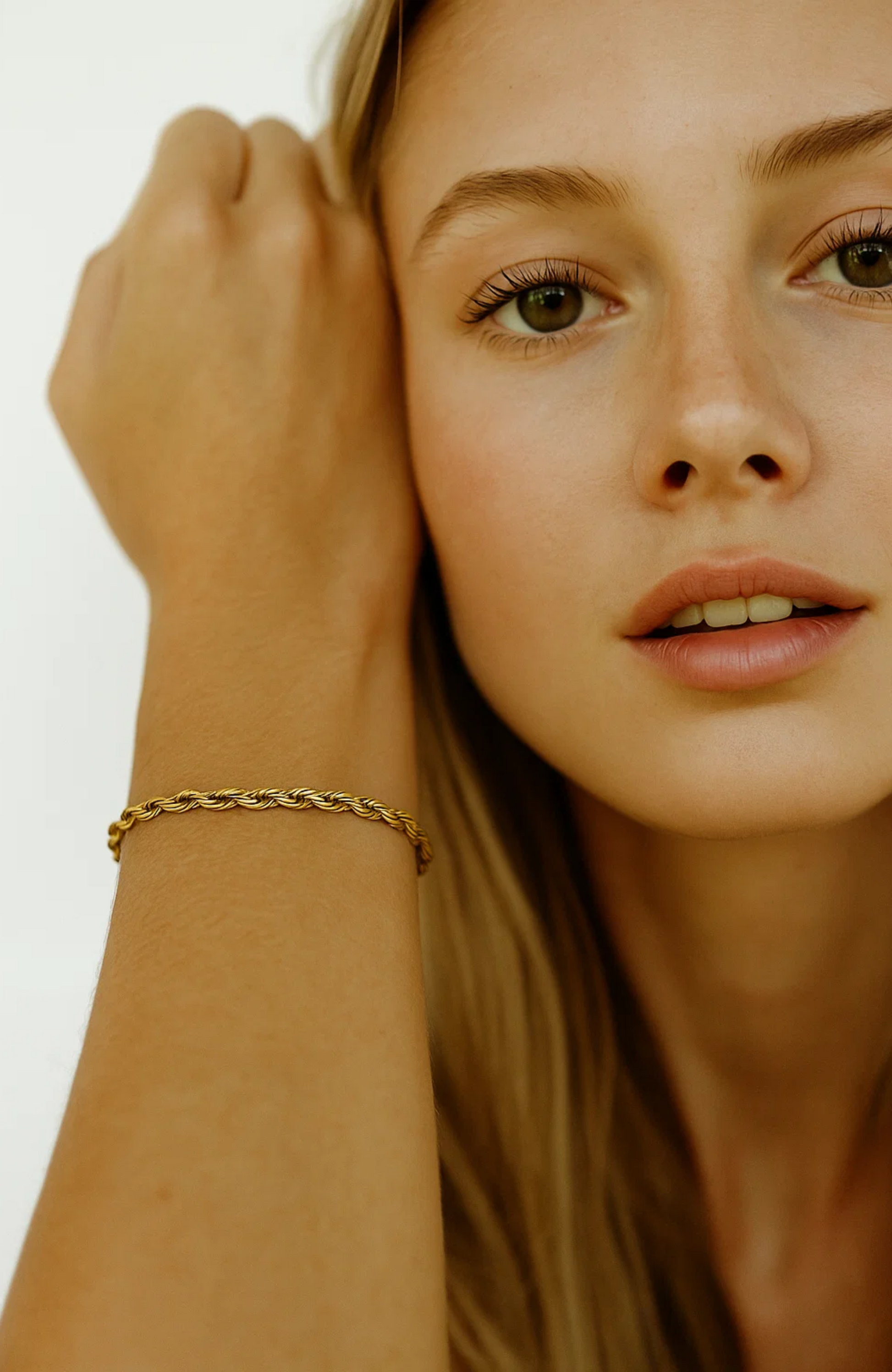 Gold rope bracelet on wrist with close face view