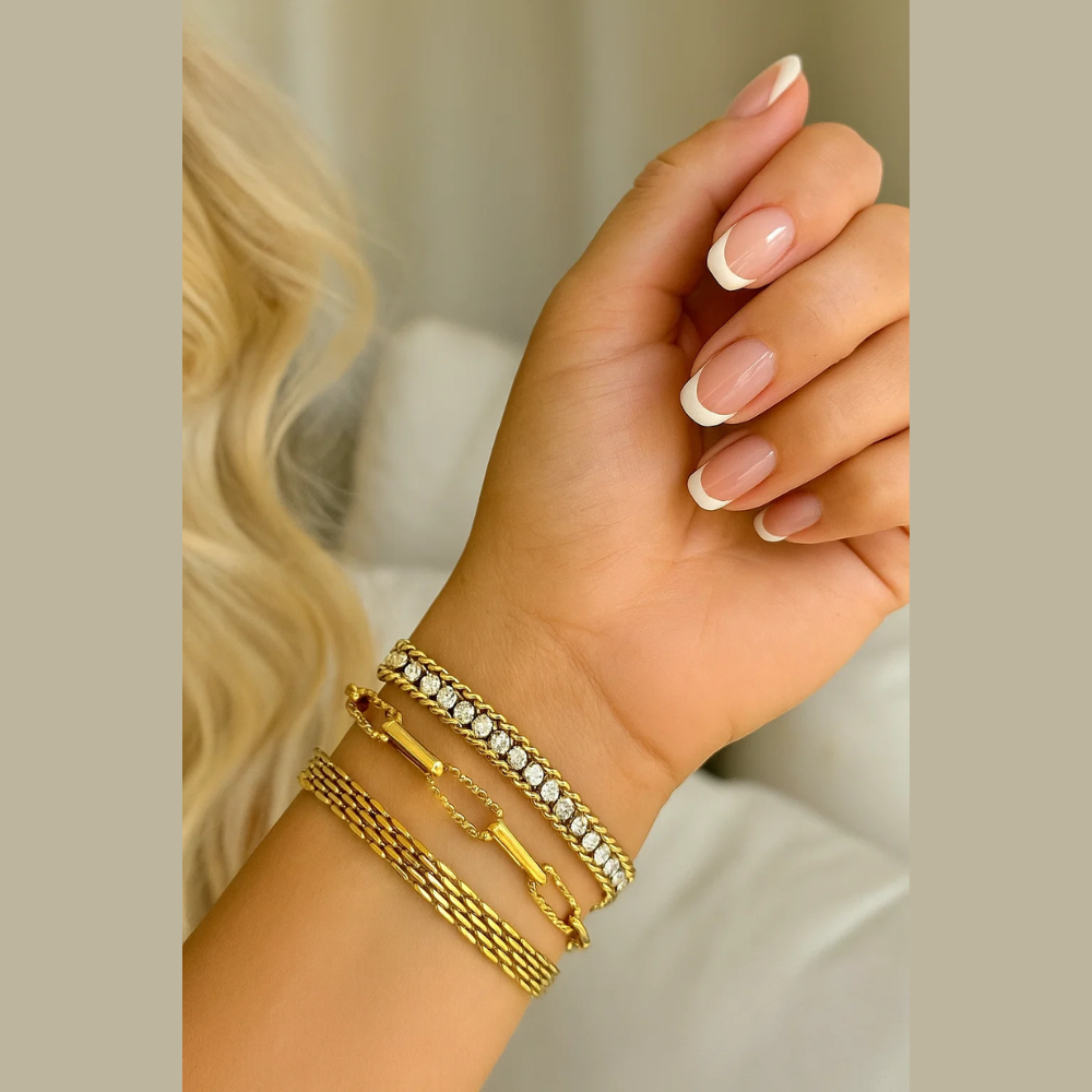 Gold-tone wide CZ chain bracelet with clear stones and adjustable bar clasp on wrist.