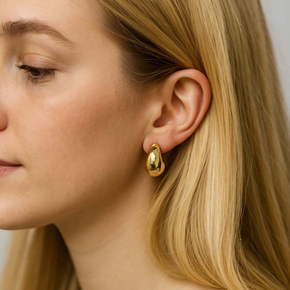 Gold dome huggie hoop earrings close-up at ear