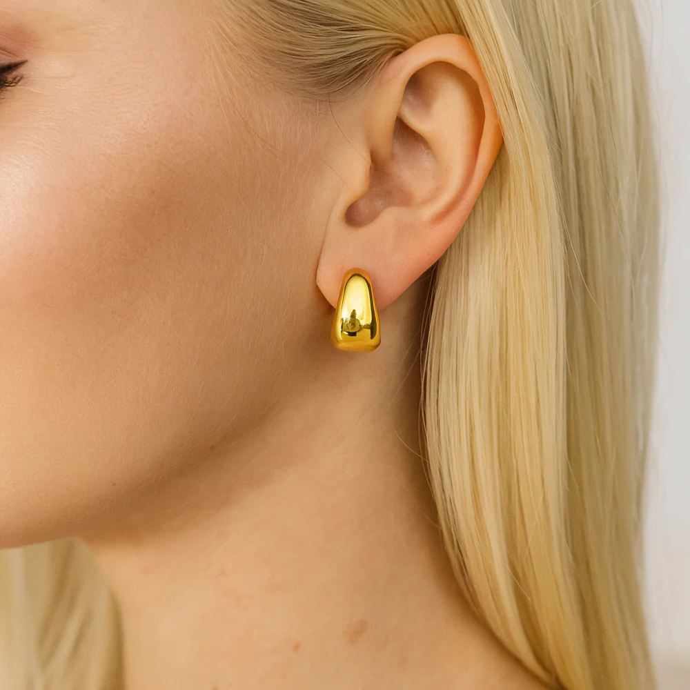 Gold dome huggie hoop earrings on model ear