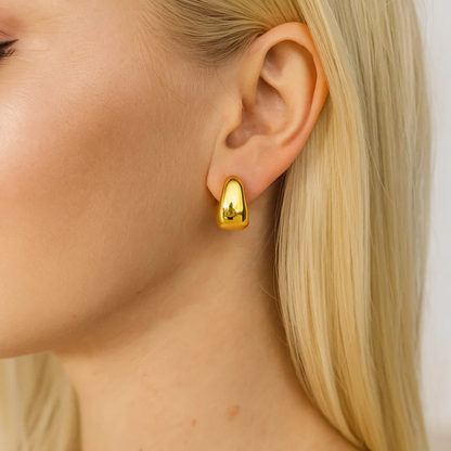 Gold dome huggie hoop earrings on model ear