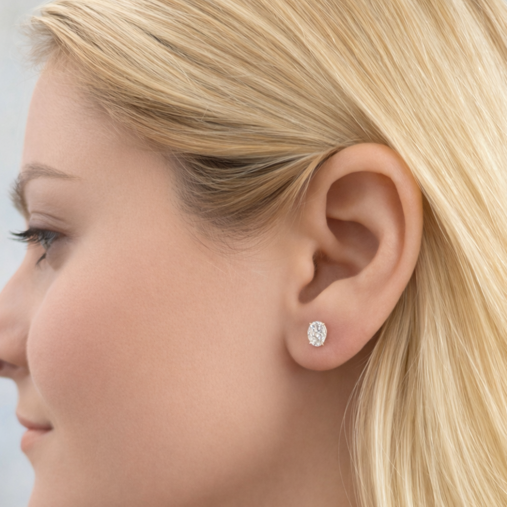 Gold oval-cut moissanite stud earrings on ear, profile view