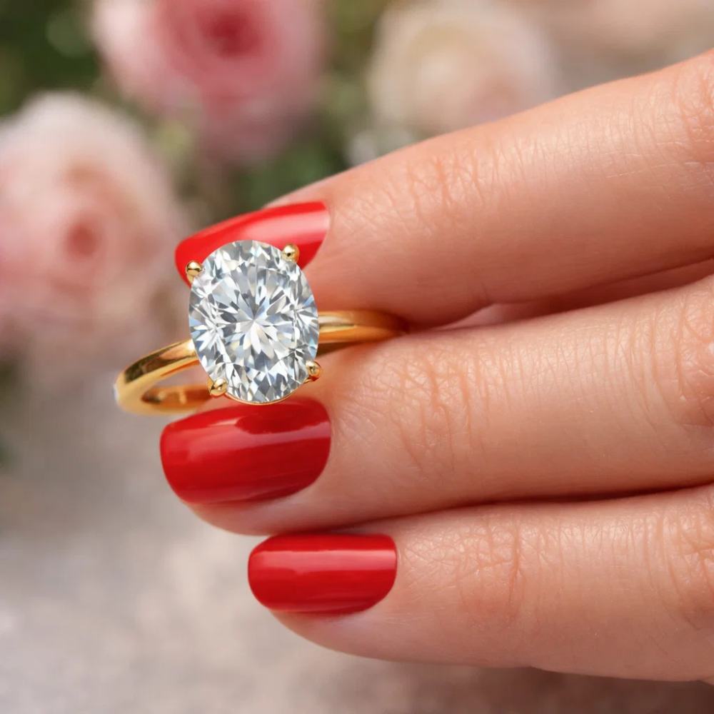 Gold-tone oval cut solitaire ring with four-prong gemstone setting on finger