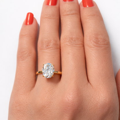 Gold-tone oval cut solitaire ring with four-prong gemstone setting on hand
