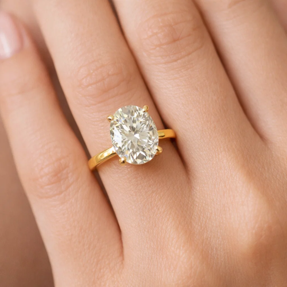 Gold-tone oval cut solitaire ring with four-prong setting, viewed from a top angle