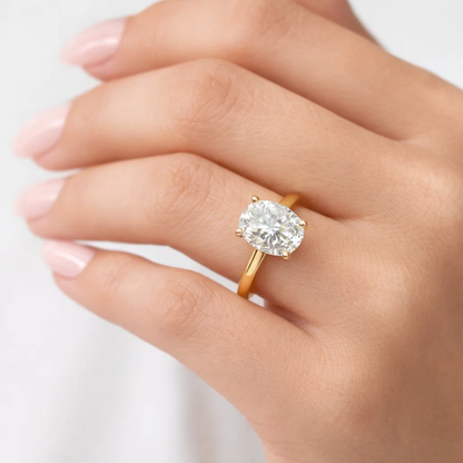 Gold oval-cut solitaire ring on finger with four-prong setting