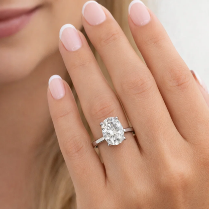 Silver-tone oval cut solitaire ring with four-prong gemstone setting on finger