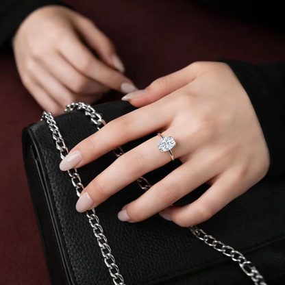 Silver oval-cut solitaire ring on finger with four-prong setting