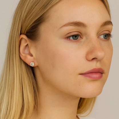 Gold-tone round crystal stud earrings on ear