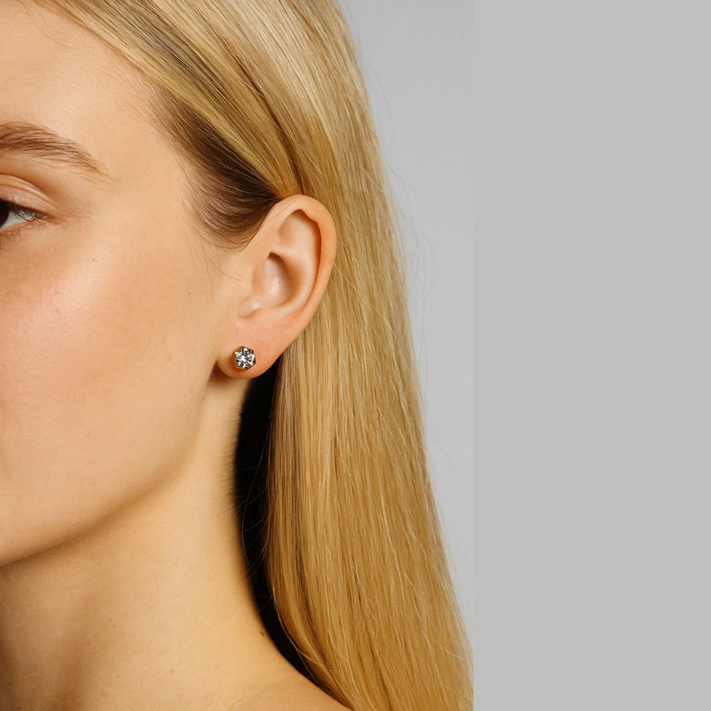 Silver-tone round crystal stud earrings on ear with blonde hair