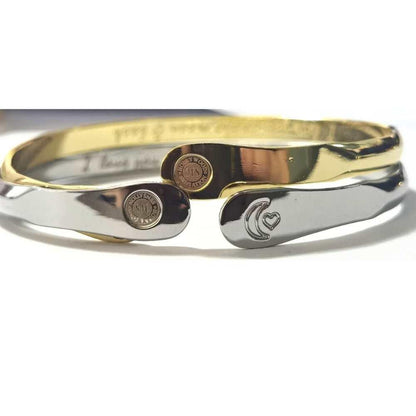 Gold and silver tone stacked cuff bracelet with moon-heart engraving and medallions