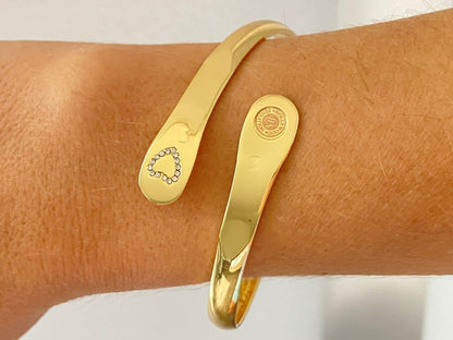 Gold mother-daughter bracelet set on wrist, heart rhinestone detail and round emblem