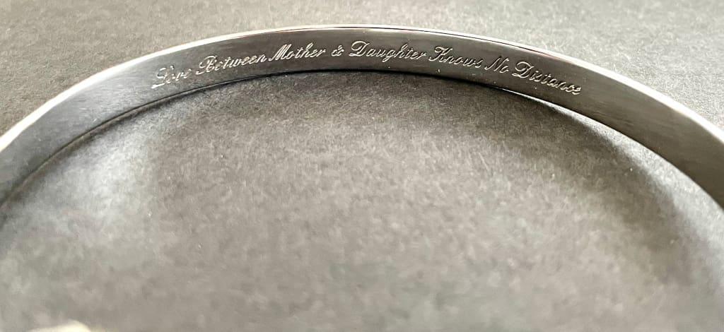 Close-up of engraved text on a silver mother-daughter bracelet cuff