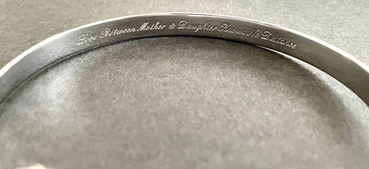 Close-up of engraved text on inner silver bracelet band