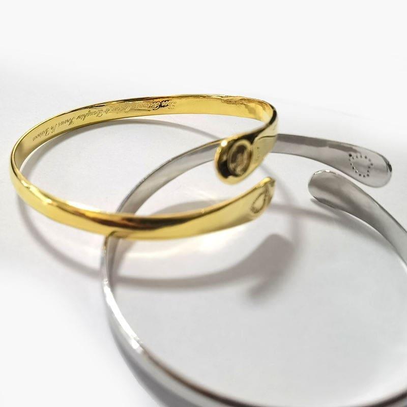 Close-up of gold and silver engraved cuffs with a circular heart emblem on one end