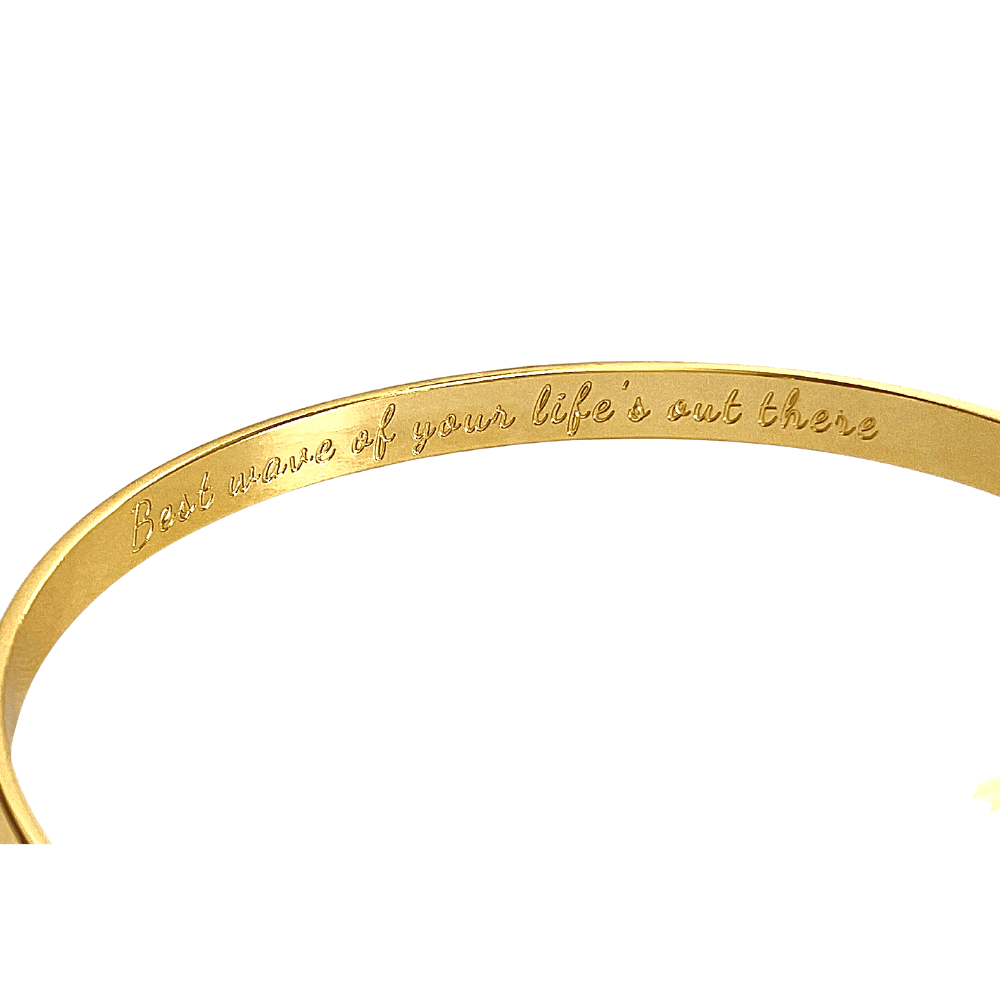 Gold cuff bracelet showing inner engraved motto along the band
