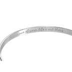 Silver cuff bracelet showing inner engraved motto along the band