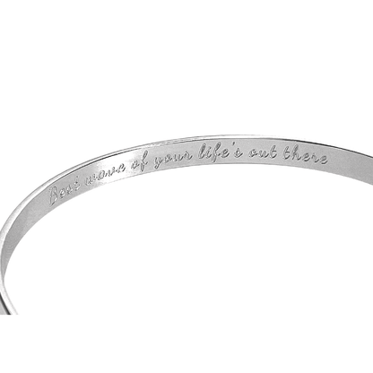 Silver cuff bracelet showing inner engraved motto along the band