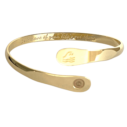 Gold wave-engraved cuff bracelet with oval wave emblem and round logo disc.
