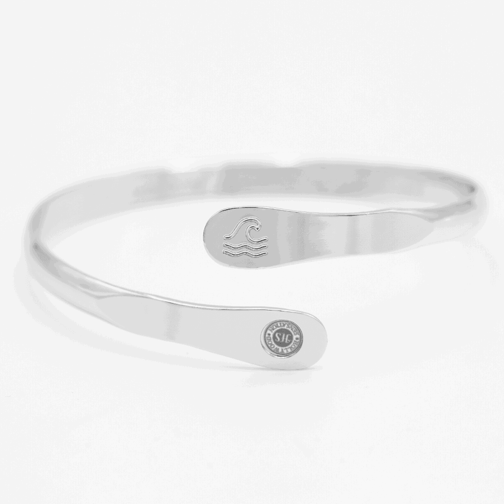Silver wave-engraved cuff bracelet with oval wave emblem and round logo disc.