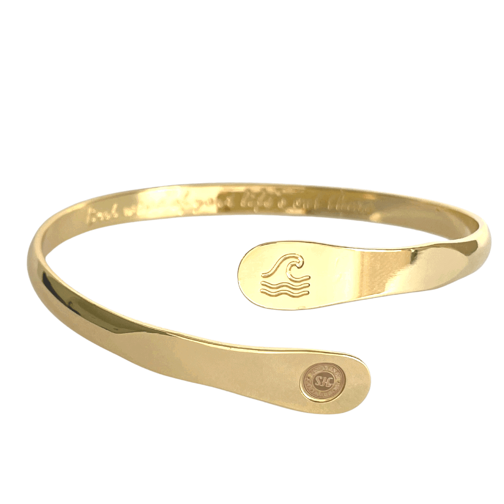 Gold wave-engraved cuff bracelet with oval wave emblem and round logo side disc.