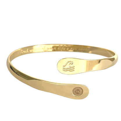 Gold wave-engraved cuff bracelet with oval wave emblem and round logo side disc.