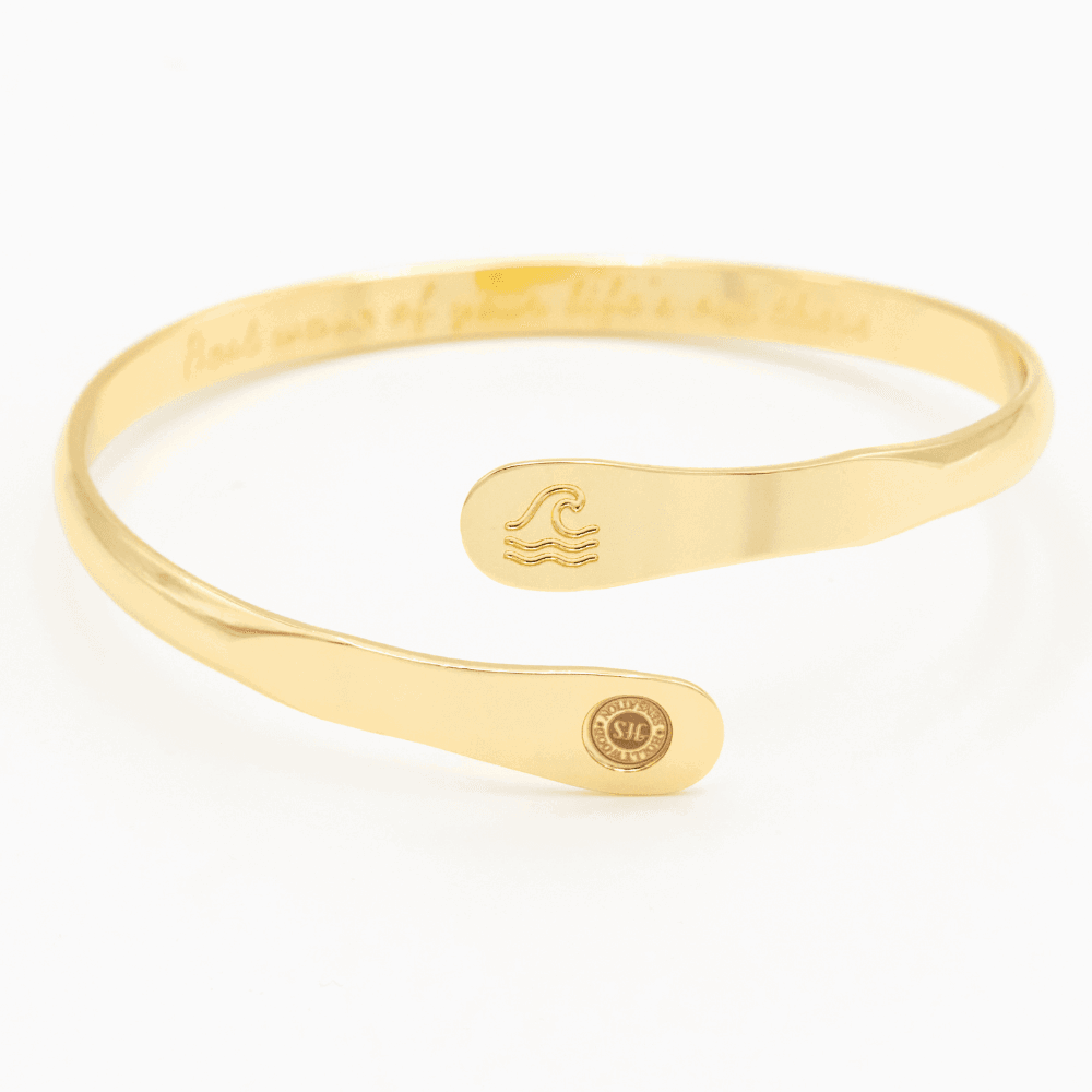 Gold wave engraved cuff bracelet with wave icon center and round side logo tag