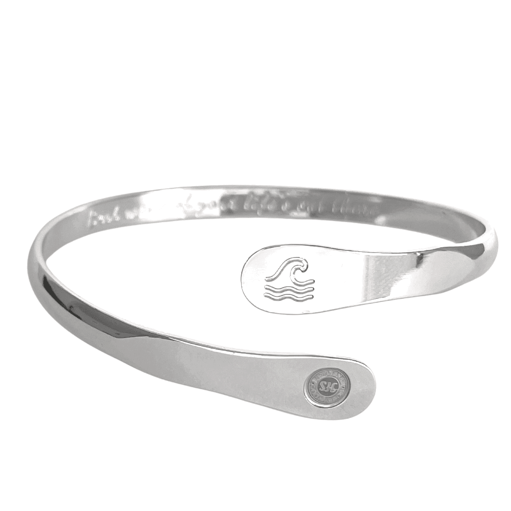 Silver wave-engraved cuff bracelet with oval wave emblem and round logo side disc.