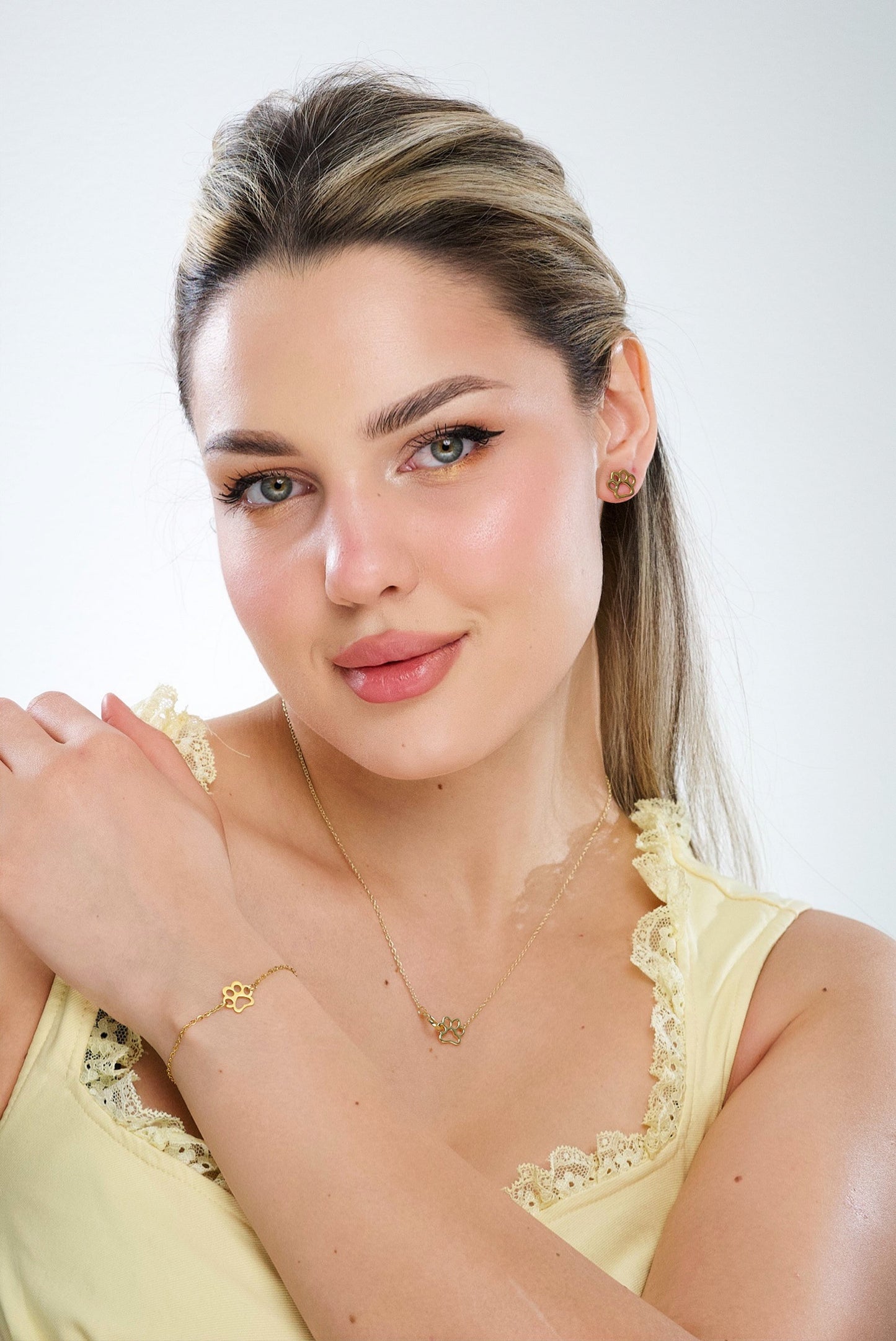 Gold paw print charm bracelet on wrist with link chain