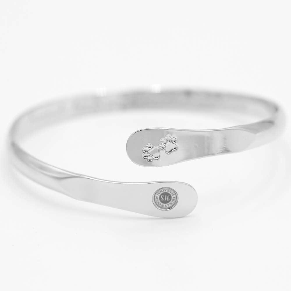 Silver cuff bracelet with paw print charm and oval engraved logo detail