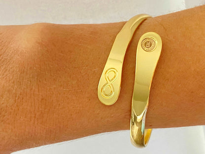 Gold infinity friendship bracelet on wrist, engraved infinity symbol and round logo charm.